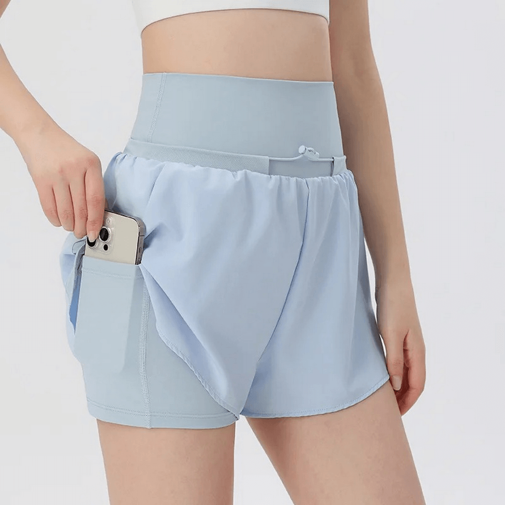 Woman wearing blue high waist athletic shorts with pocket, perfect for gym and warm weather. Ideal blend of polyester and spandex.